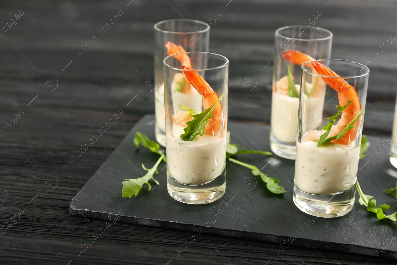 Photo of Delicious shrimp cocktail with tartar sauce served on black wooden table