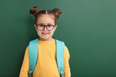 Happy little school child with backpack near chalkboard. Space for text