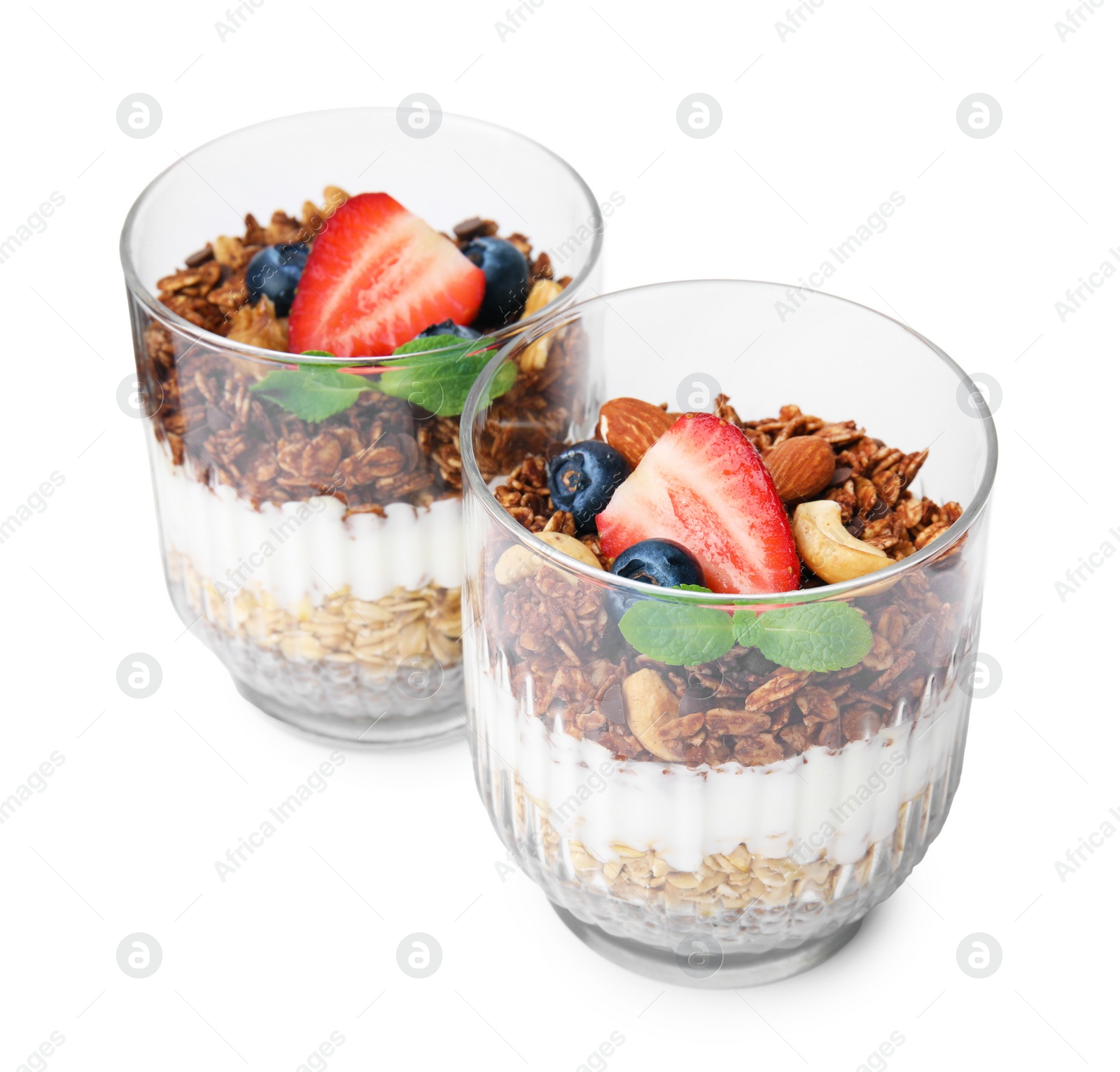 Photo of Tasty granola with berries, nuts, yogurt and chia seeds in glasses isolated on white