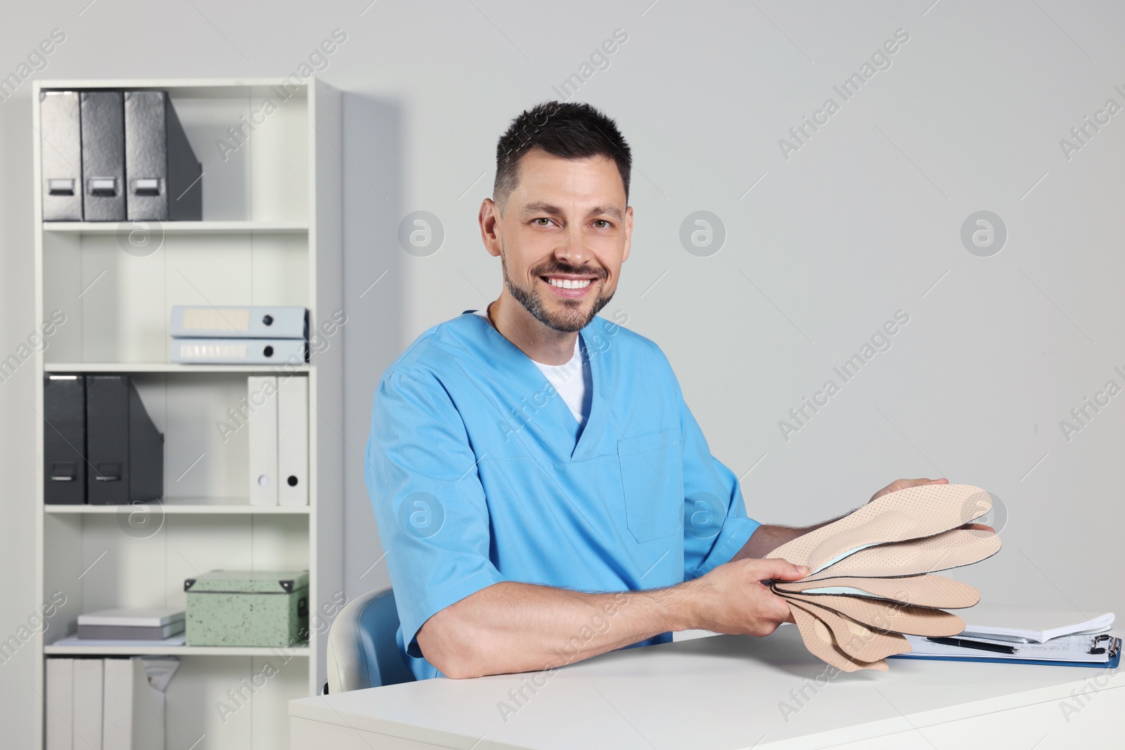 Photo of Handsome male orthopedist showing insoles in hospital