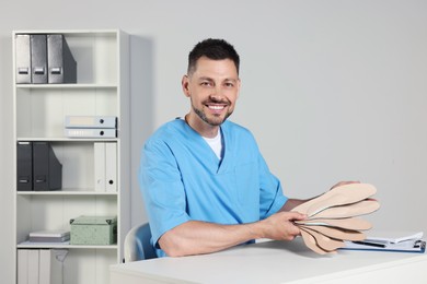 Handsome male orthopedist showing insoles in hospital