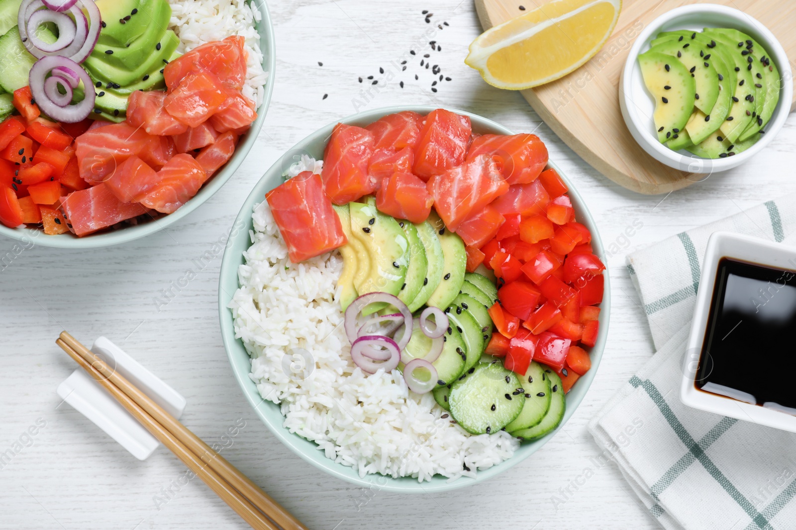 Photo of Delicious poke bowl with salmon and vegetables served on white wooden table, flat lay