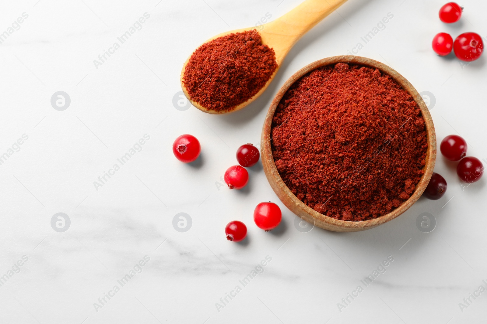 Photo of Dried cranberry powder and fresh berries on white marble table, flat lay. Space for text