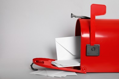 Photo of Open red letter box with envelopes on light background, closeup. Space for text