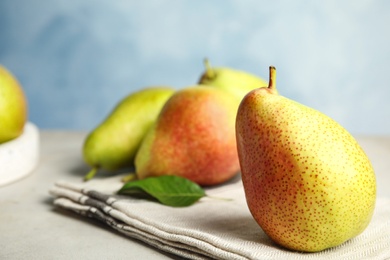 Photo of Ripe juicy pears on grey stone table against blue background, closeup. Space for text