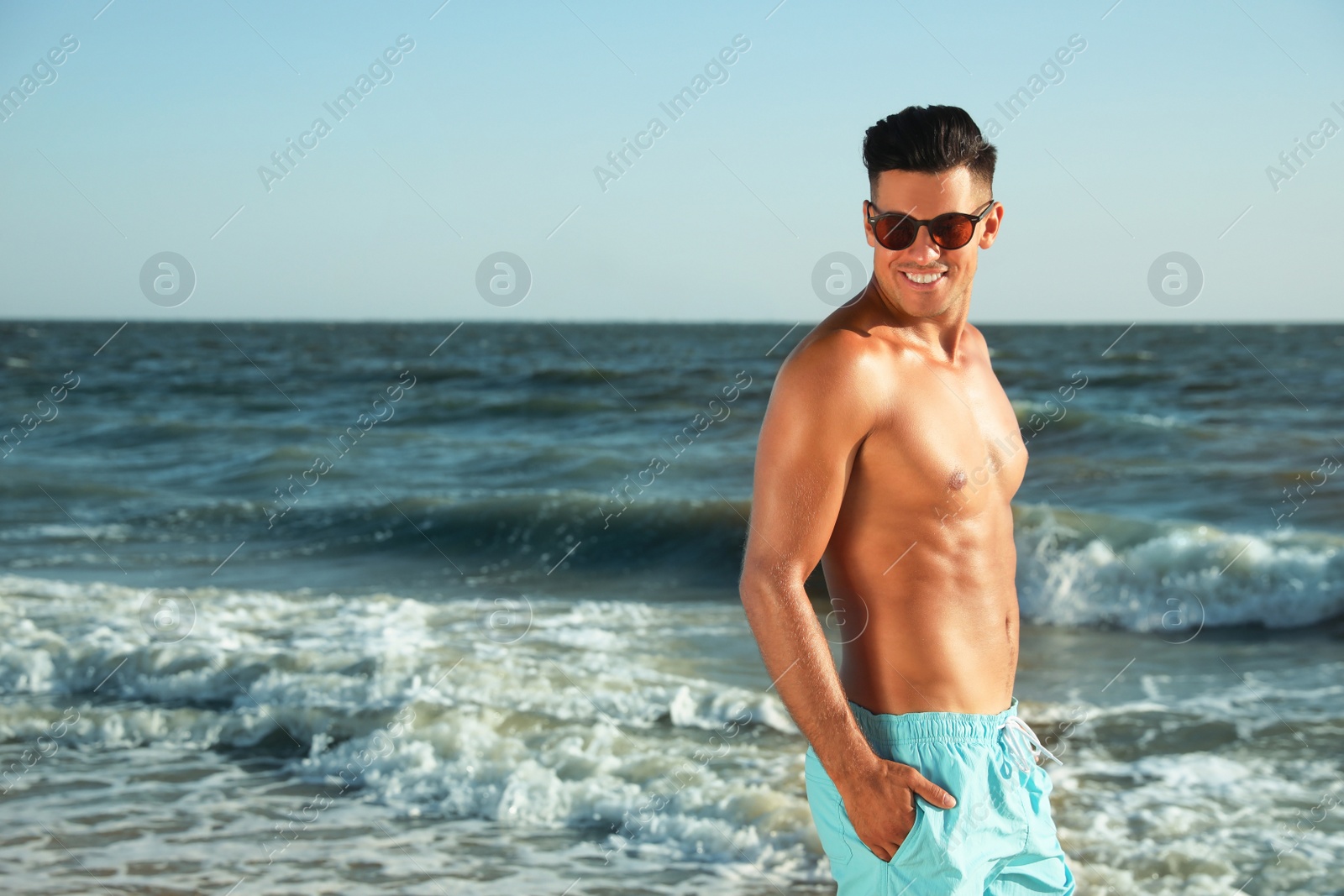 Photo of Handsome man with attractive body on beach. Space for text