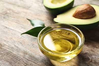 Photo of Gravy boat with oil and fresh avocado on wooden table