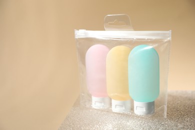Photo of Cosmetic travel kit in plastic bag on beige background, space for text. Bath accessories
