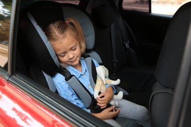 Photo of Cute little girl sleeping in child safety seat inside car