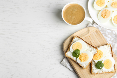 Photo of Tasty egg sandwiches served with coffee on white wooden table, flat lay. Space for text