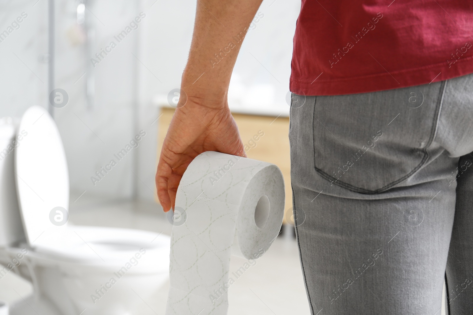 Photo of Man with paper roll near toilet bowl in bathroom, closeup