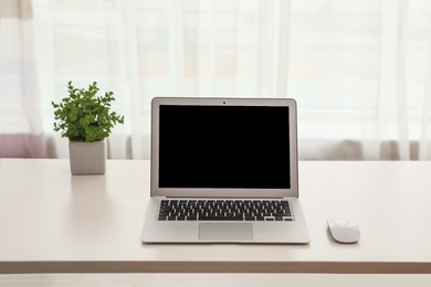 Photo of Laptop with computer mouse on table indoors. Space for text