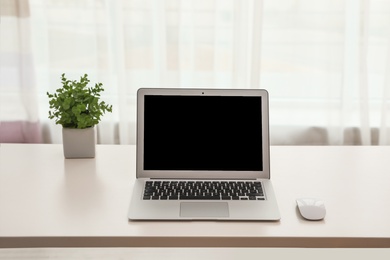 Laptop with computer mouse on table indoors. Space for text