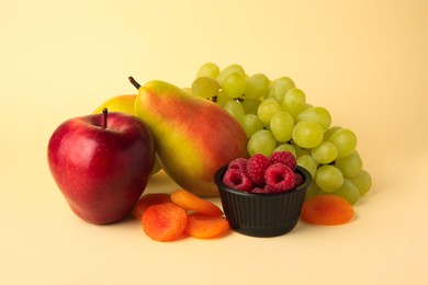 Photo of Delicious ripe fruits, raspberries and dried apricots on beige background. Fructose concept