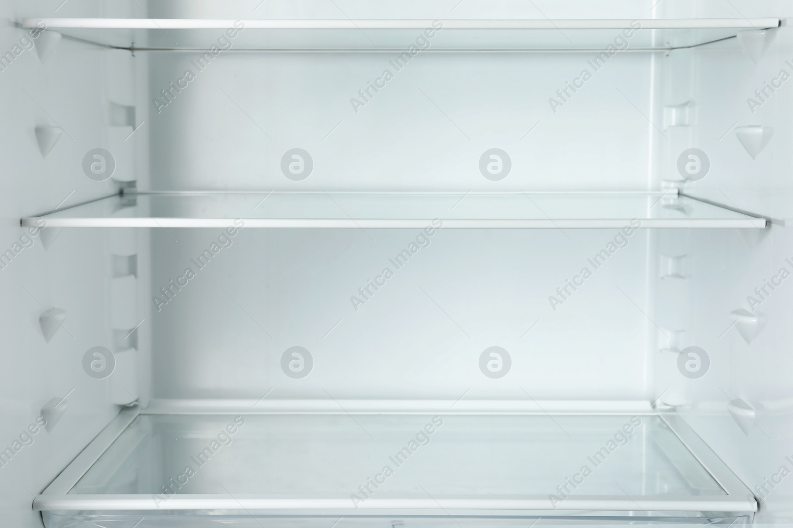 Photo of Modern open refrigerator with empty shelves, closeup