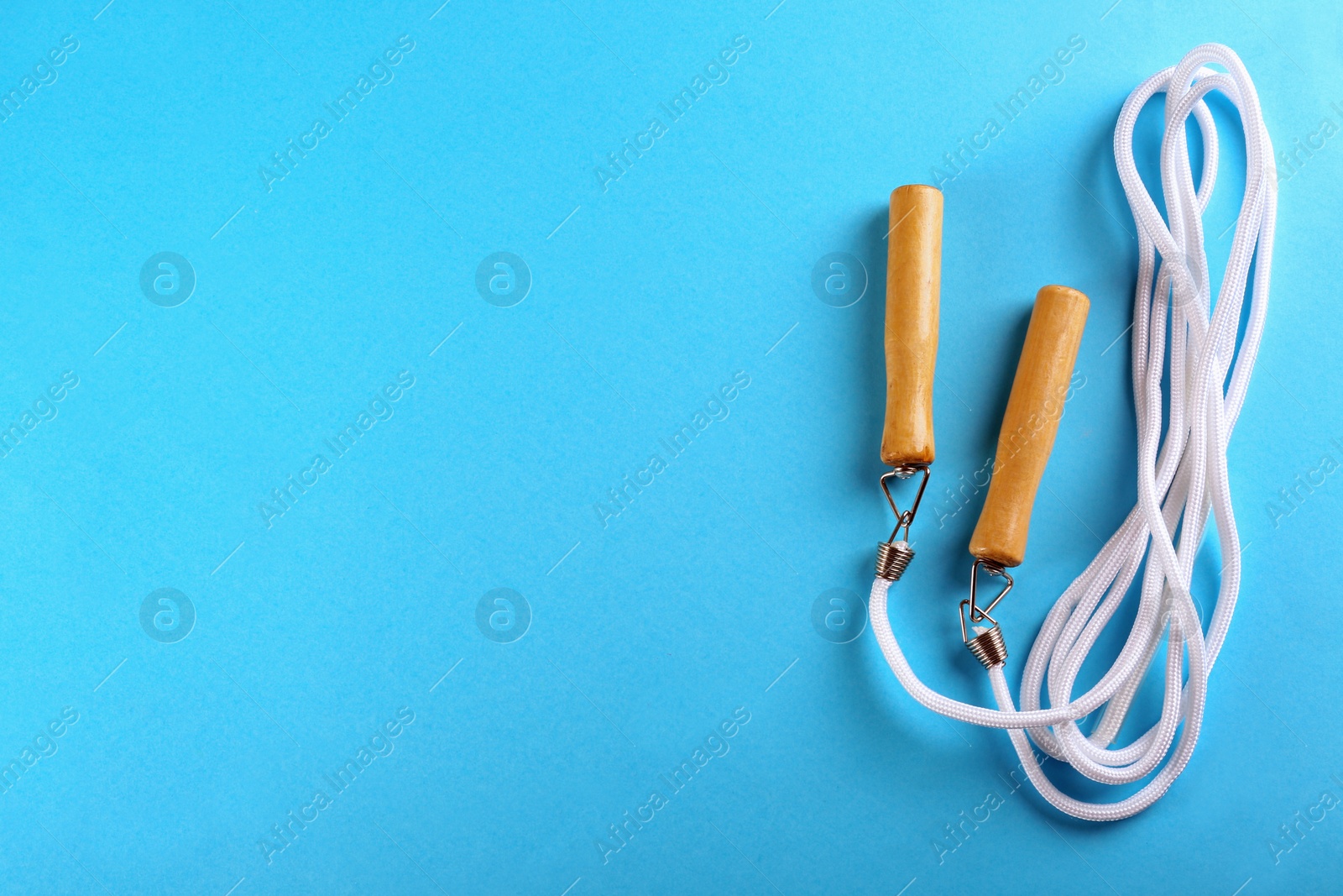 Photo of Skipping rope on light blue background, top view. Space for text