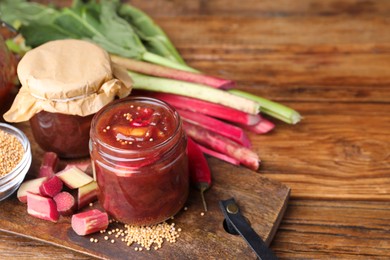 Photo of Tasty rhubarb sauce and ingredients on wooden table, space for text