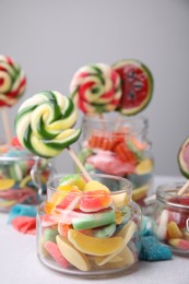 Photo of Tasty different candies in jars on light grey table