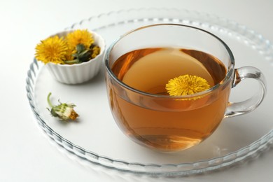 Delicious fresh tea and dandelion flowers on white table