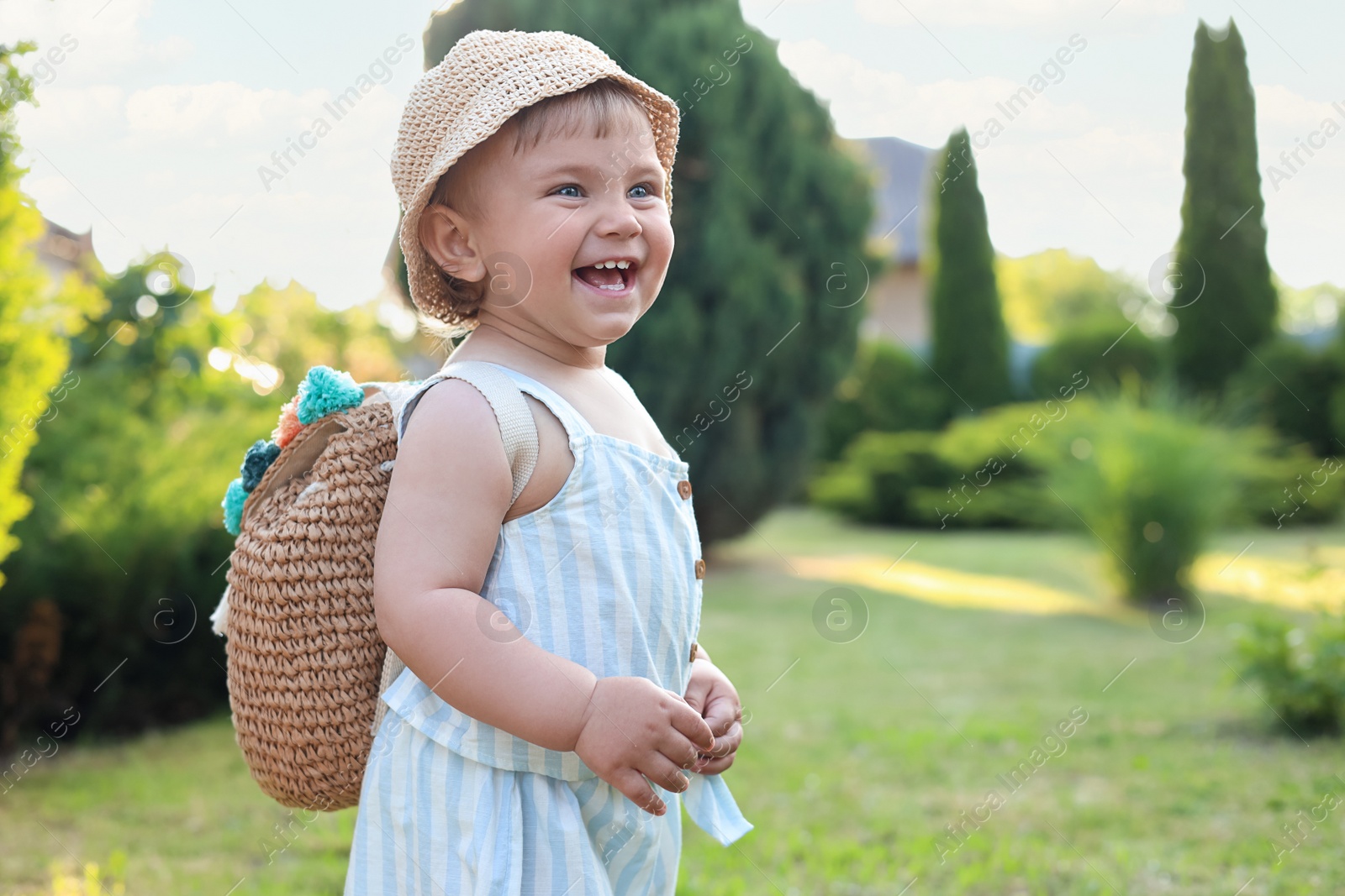 Photo of Cute little girl in stylish clothes with knitted backpack outdoors on sunny day. Space for text