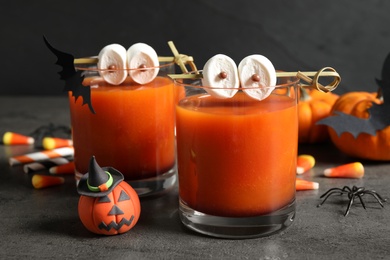 Photo of Decorated glasses with drinks on grey table, closeup. Halloween celebration