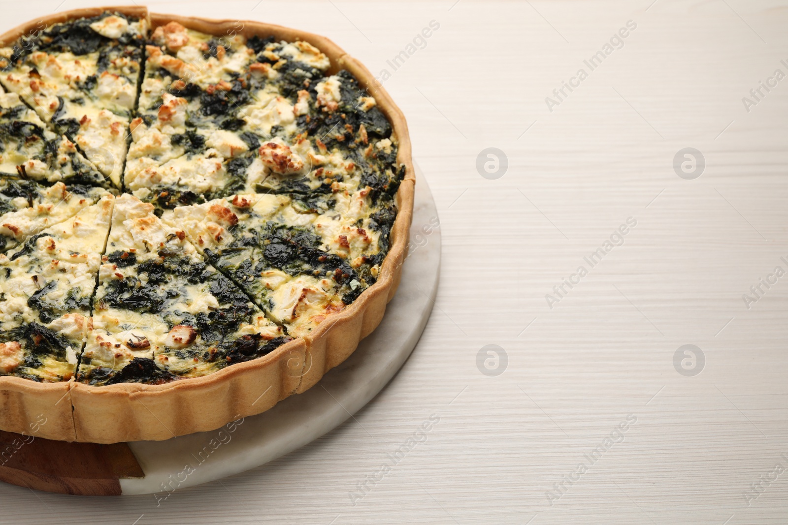 Photo of Delicious homemade spinach quiche on white wooden table, space for text
