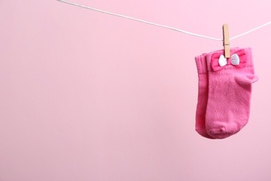 Small socks hanging on washing line against color background, space for text. Baby accessories