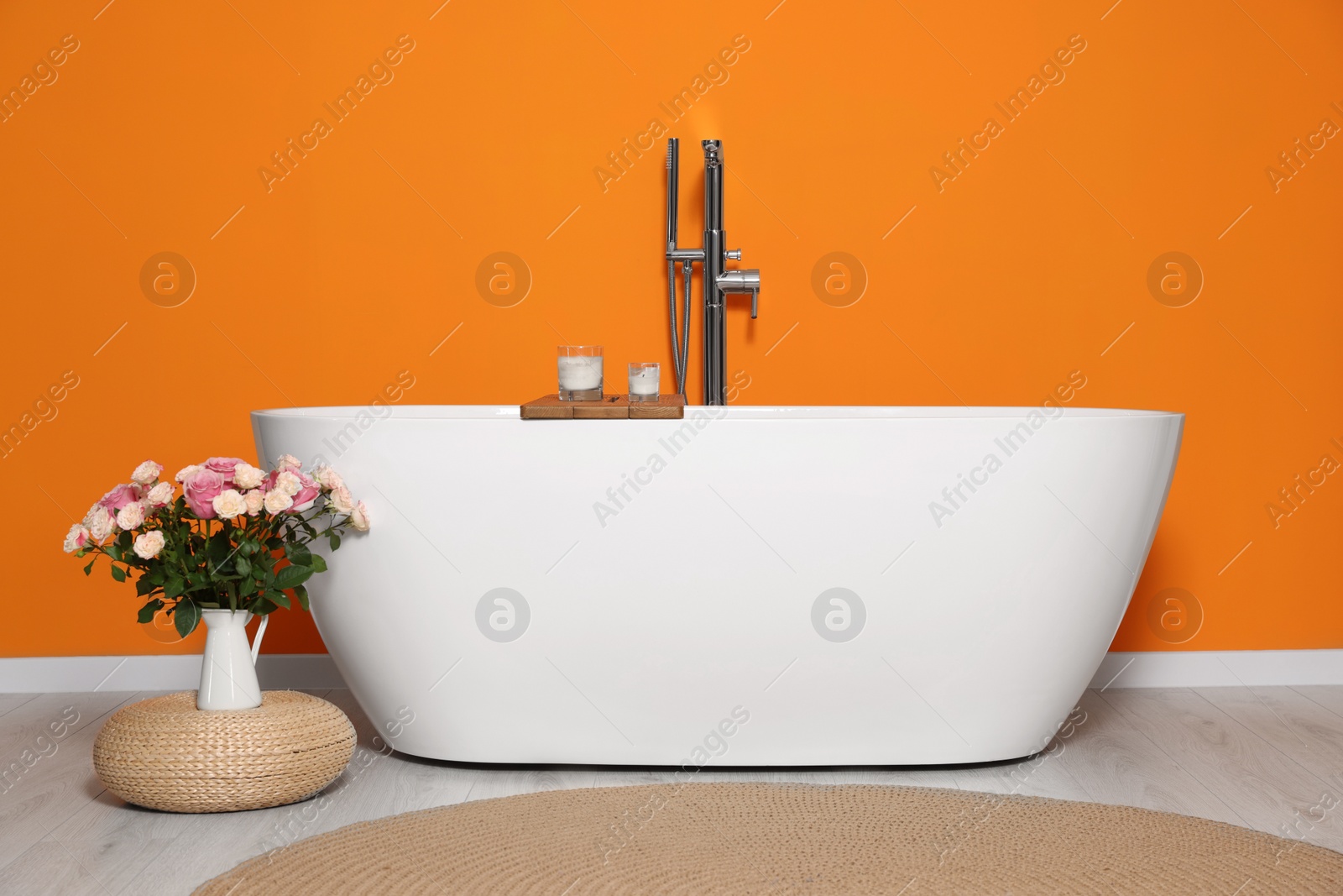 Photo of Stylish bathroom interior with ceramic tub and beautiful bouquet of roses