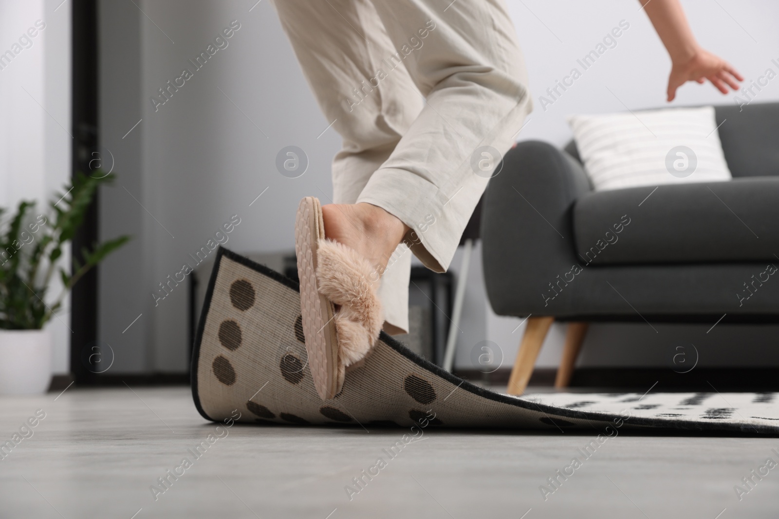 Photo of Woman tripping over carpet at home, closeup