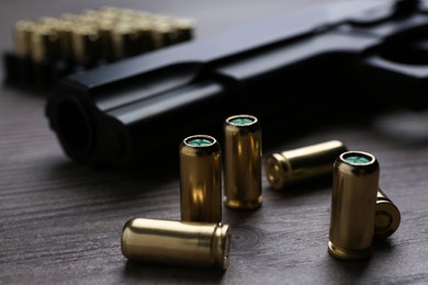 Photo of Pistol bullets on wooden table, closeup. Professional gun