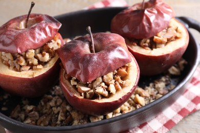 Photo of Tasty baked apples with nuts in baking dish on table, closeup