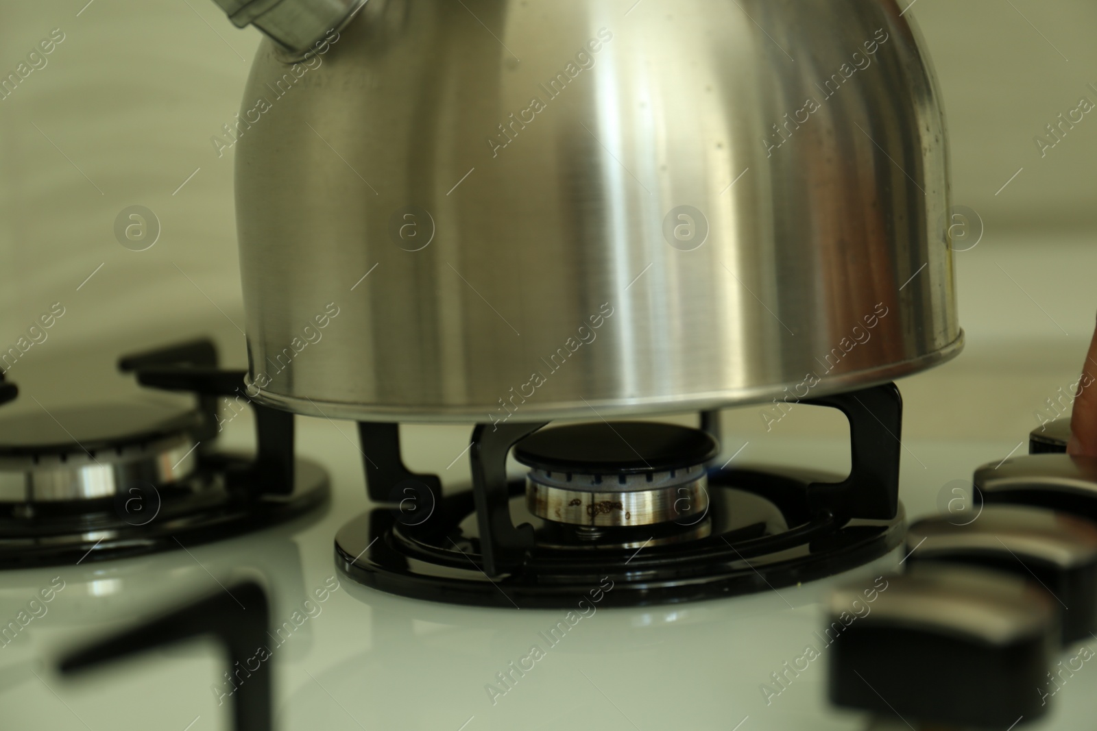 Photo of Kettle on gas burner of stove in kitchen, closeup