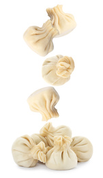 Many tasty dumplings falling on white background