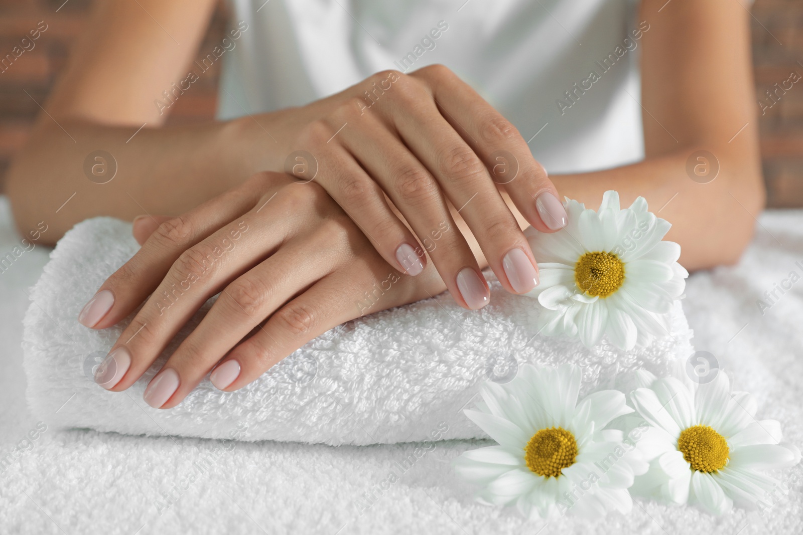 Photo of Woman with smooth hands and flowers on towel, closeup. Spa treatment