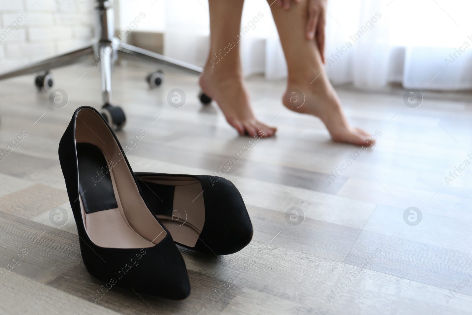 Photo of Barefoot woman in office, closeup with focus on shoes. Tired feet after wearing high heels