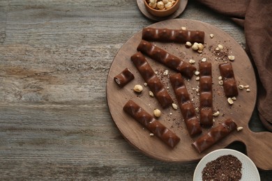 Photo of Tasty chocolate bars with nuts on wooden table, flat lay. Space for text