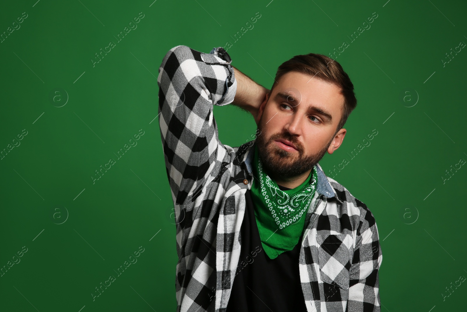 Photo of Fashionable young man in stylish outfit with bandana on green background