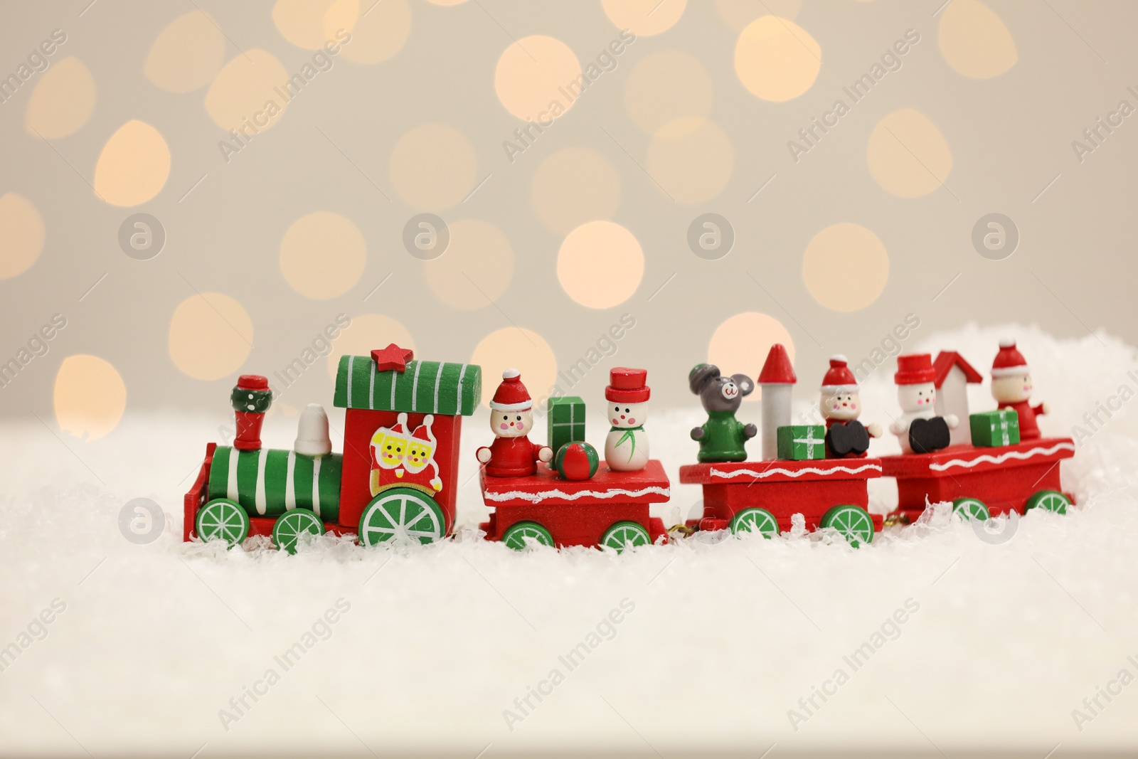 Photo of Toy train on artificial snow against Christmas lights