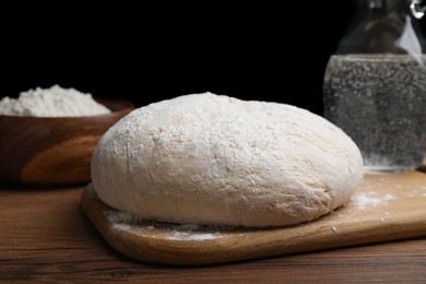 Photo of Dough on wooden table against black background. Sodawater bread recipe