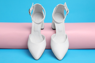 Stylish white female shoes on light blue background