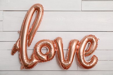 Beautiful pink foil balloon in shape of word Love near white wall. Valentine's Day celebration