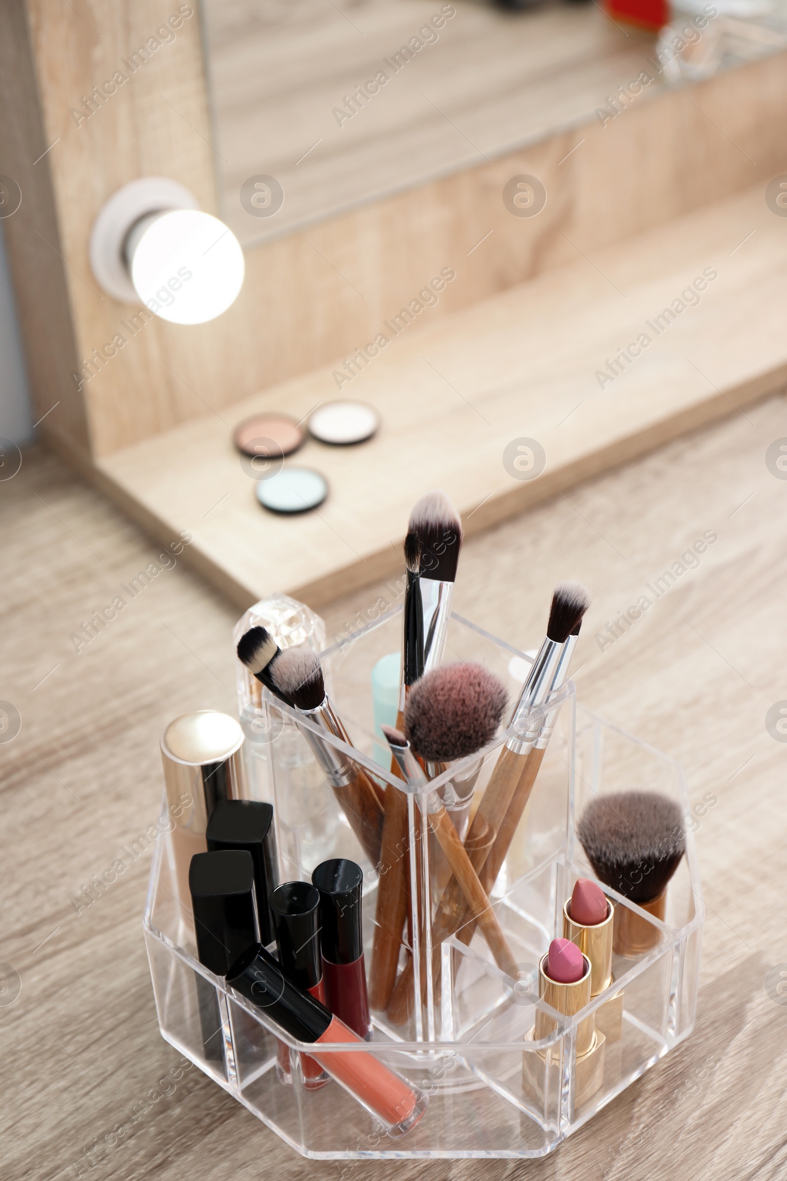 Photo of Organizer with cosmetic products for makeup on table near mirror