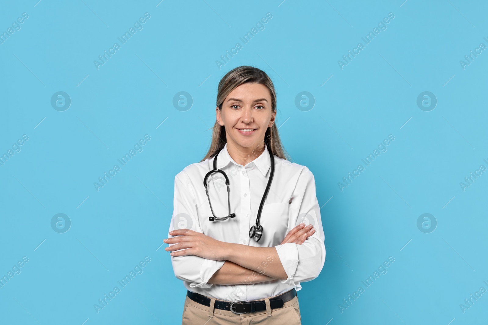 Photo of Portrait of happy doctor with stethoscope on light blue background