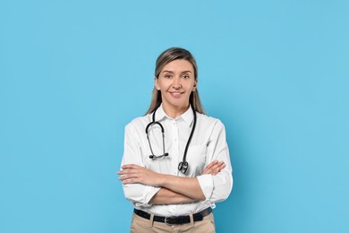 Portrait of happy doctor with stethoscope on light blue background