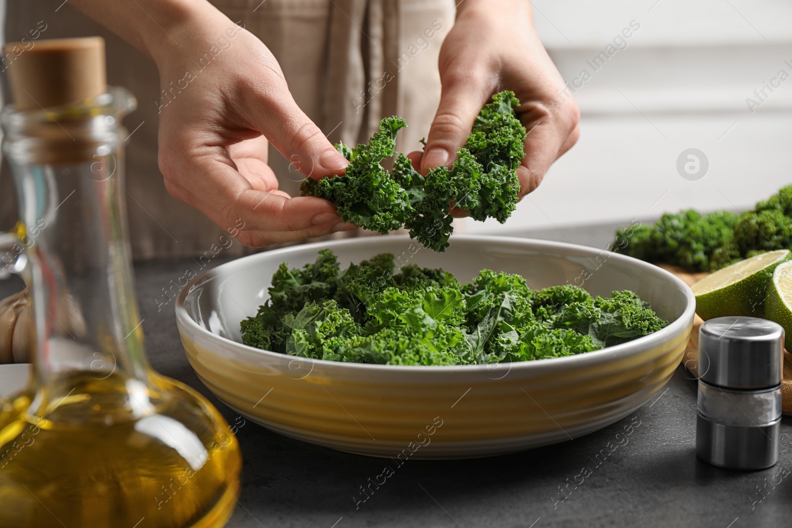 Photo of Woman cooking tasty kale salad on grey table, closeup