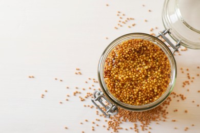 Photo of Jar of whole grain mustard on white wooden table, top view. Space for text