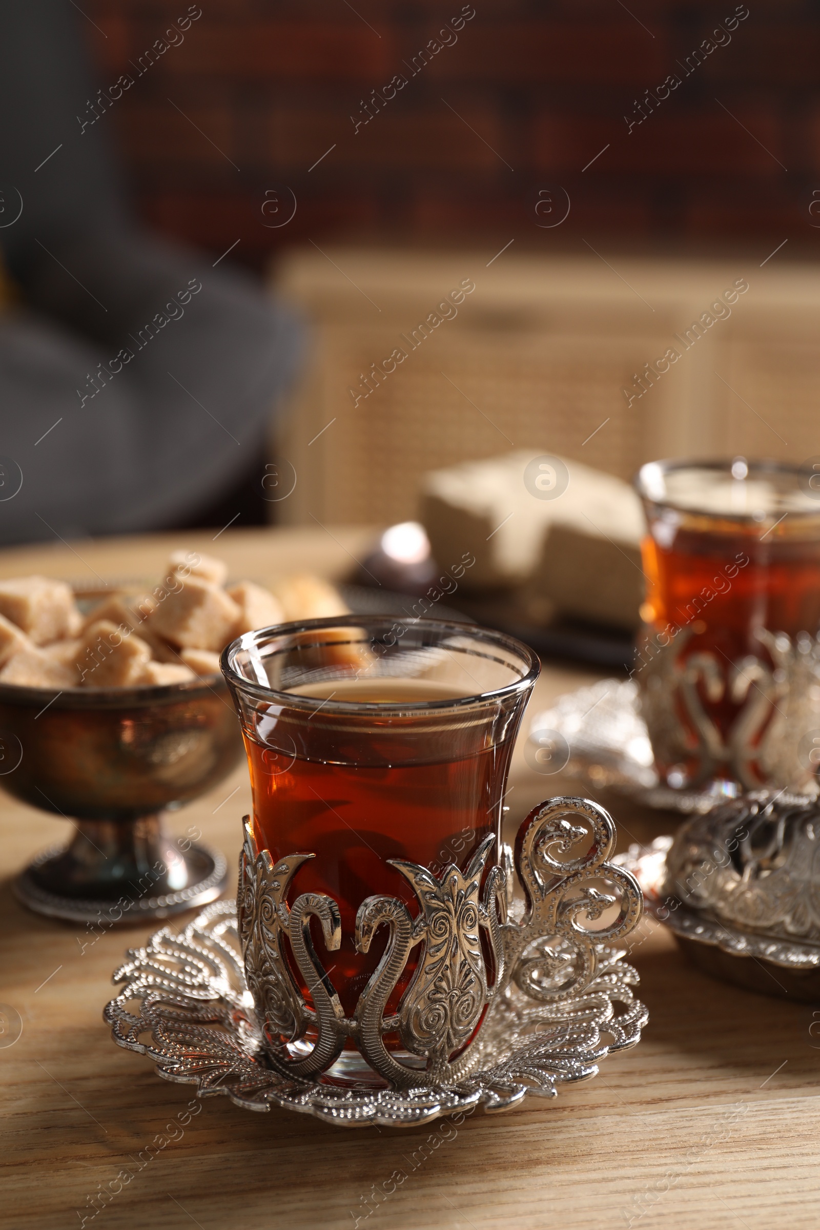 Photo of Glasses of traditional Turkish tea in vintage holders on wooden table