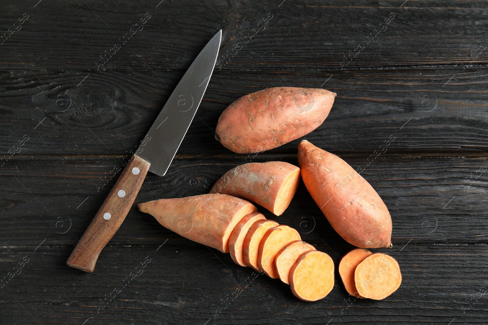 Photo of Flat lay composition with sweet potatoes and knife on wooden background