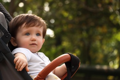 Photo of Cute little child in baby stroller outdoors