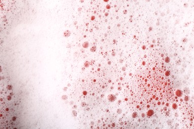 Photo of White foam with bubbles on red background, above view